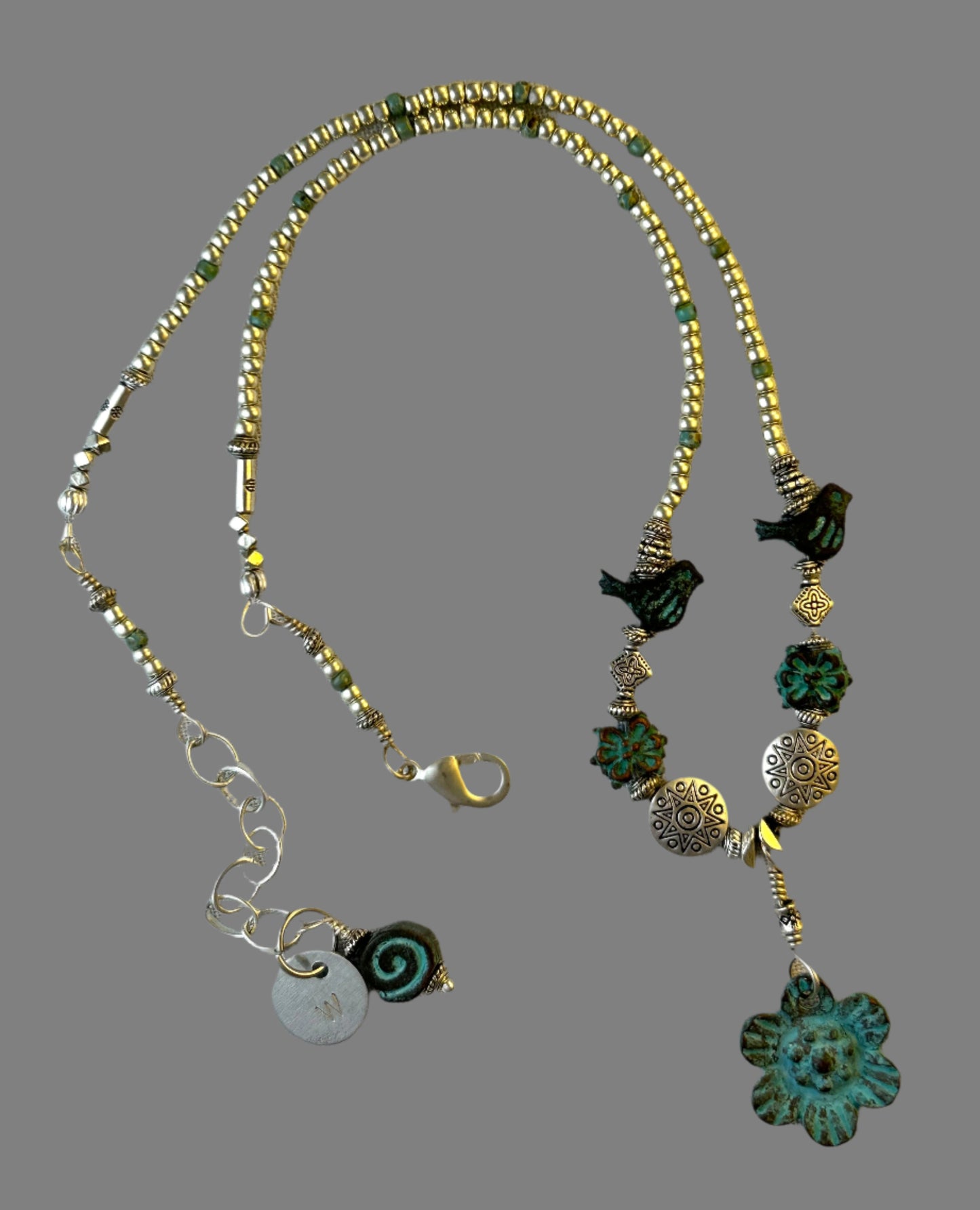 A choker necklace with turquoise patina flower and silver charms, silver beads, and a silver lobster clasp.