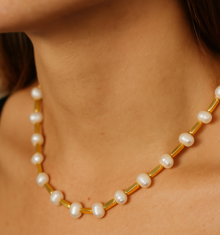 Pearl necklace with gold accents on a person's neck